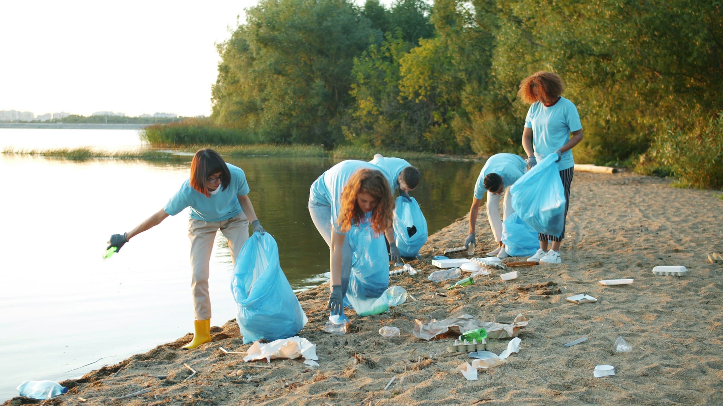 Relawan muda memungut sampah plastik di tepi danau saat sore hari